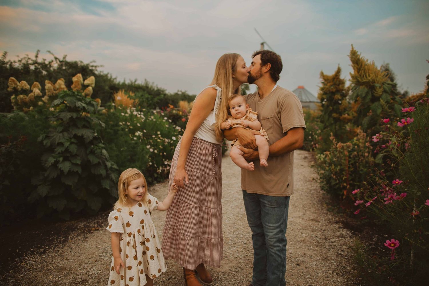 Candid family photos taken along a garden path with blooming flowers in the background.