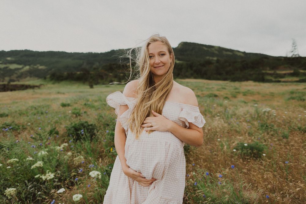 A series of outdoor maternity photos showing a woman in a white dress against rolling green hills and fields.