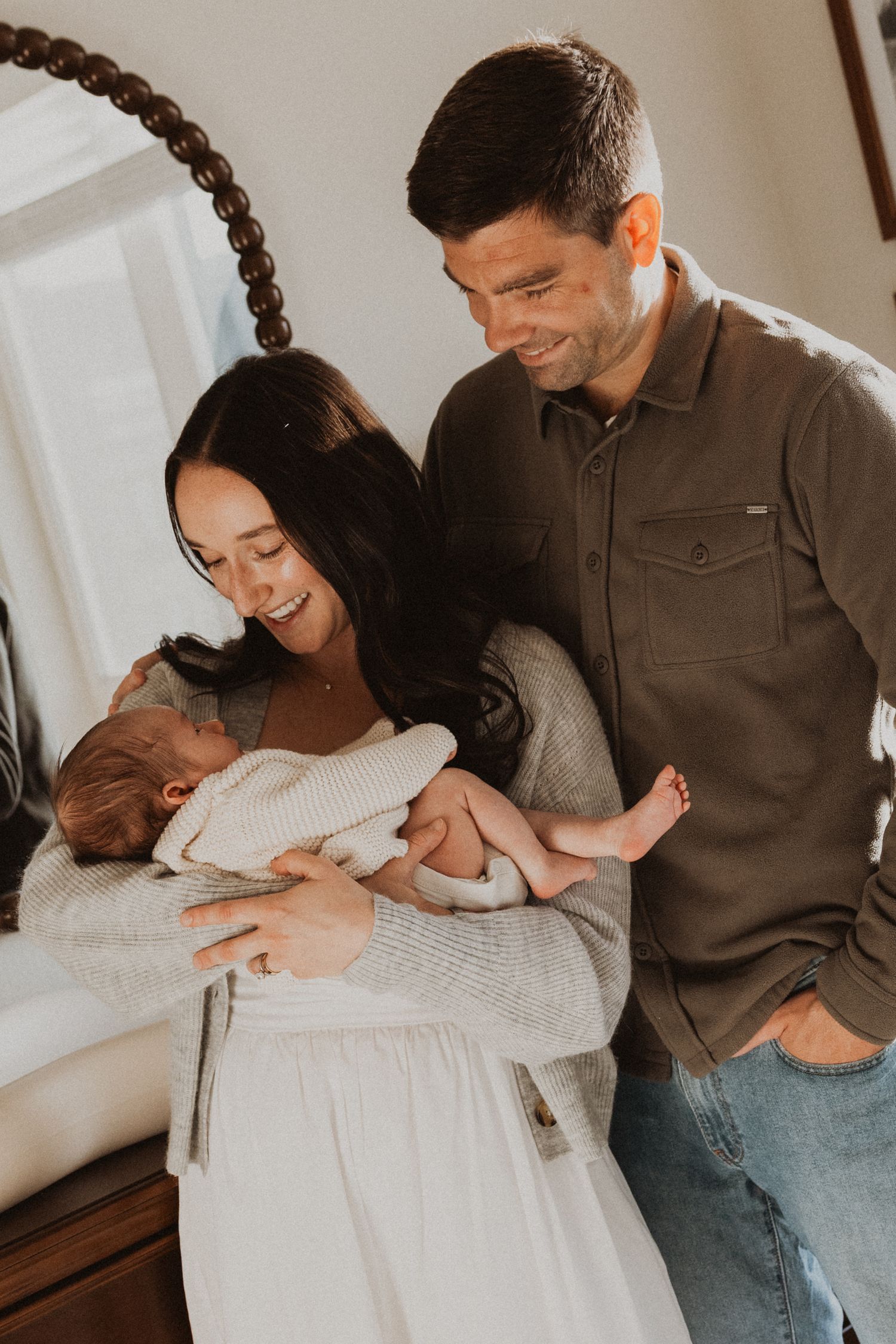 Happy couple smiling at their newborn baby in a cozy home setting.
