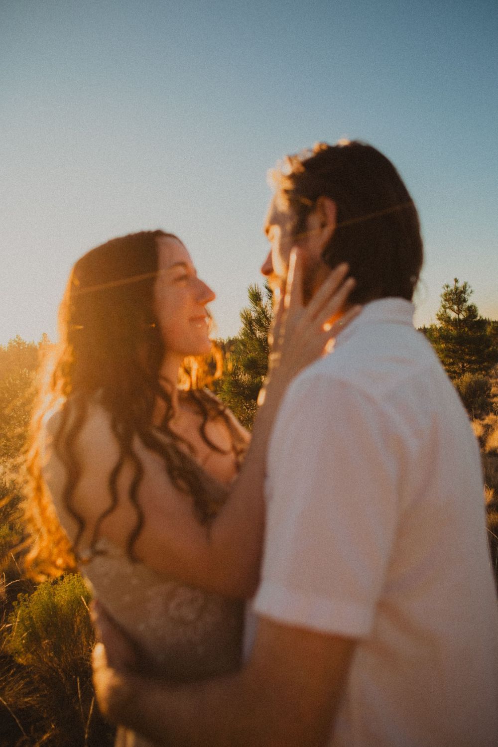 Silhouettes of a couple kissing during golden hour in a desert landscape.