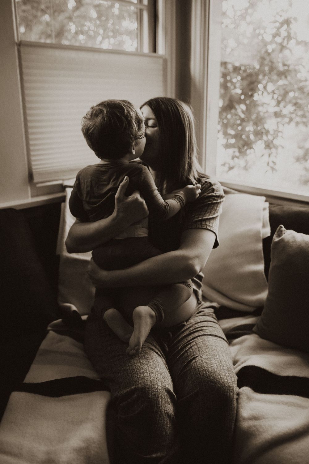 Tender moment shared on a comfortable couch in natural window light.