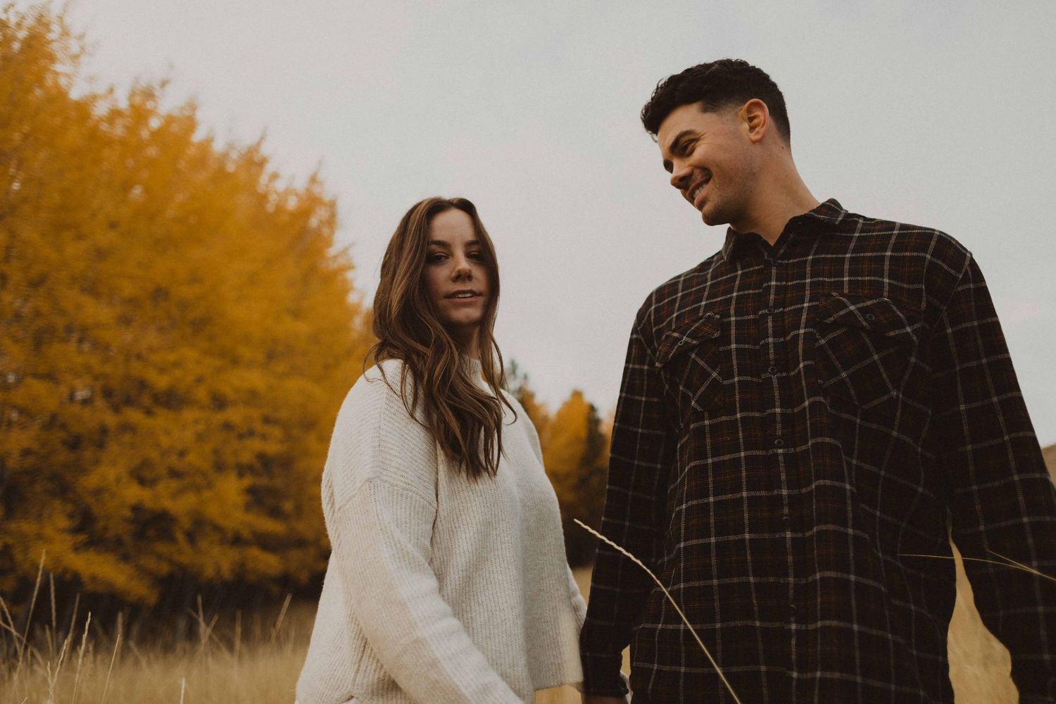 A romantic autumn photoshoot in a field with warm golden foliage and natural lighting.