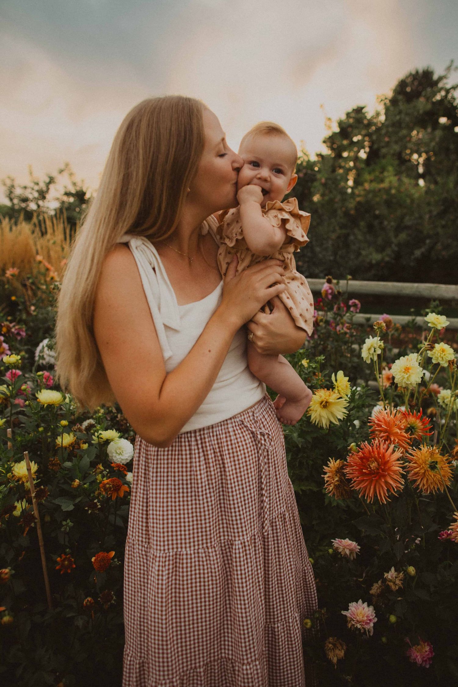 Tender family moments captured in a garden filled with vibrant dahlias and flowers at sunset.