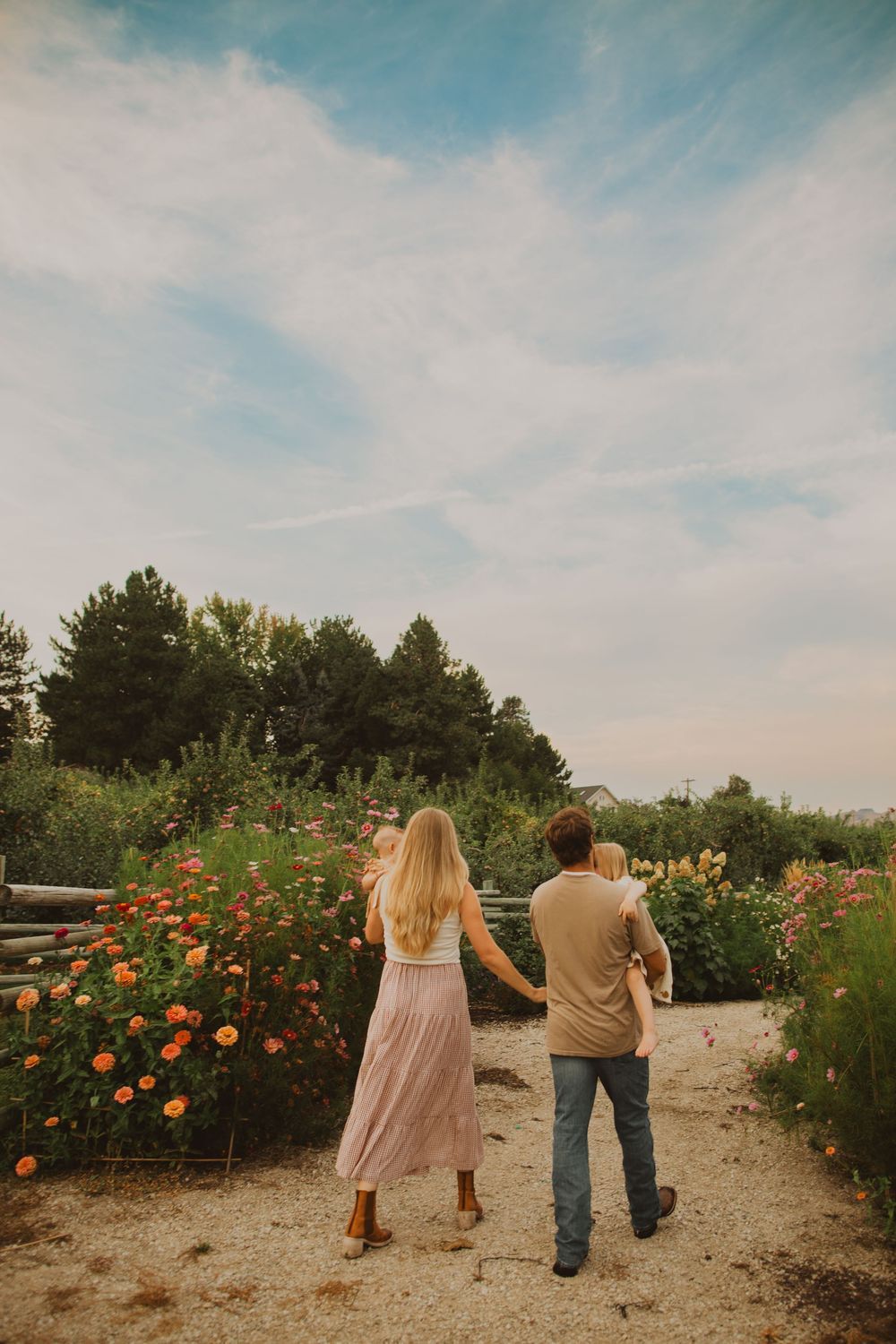 Family walking together down a garden path surrounded by blooming flowers.