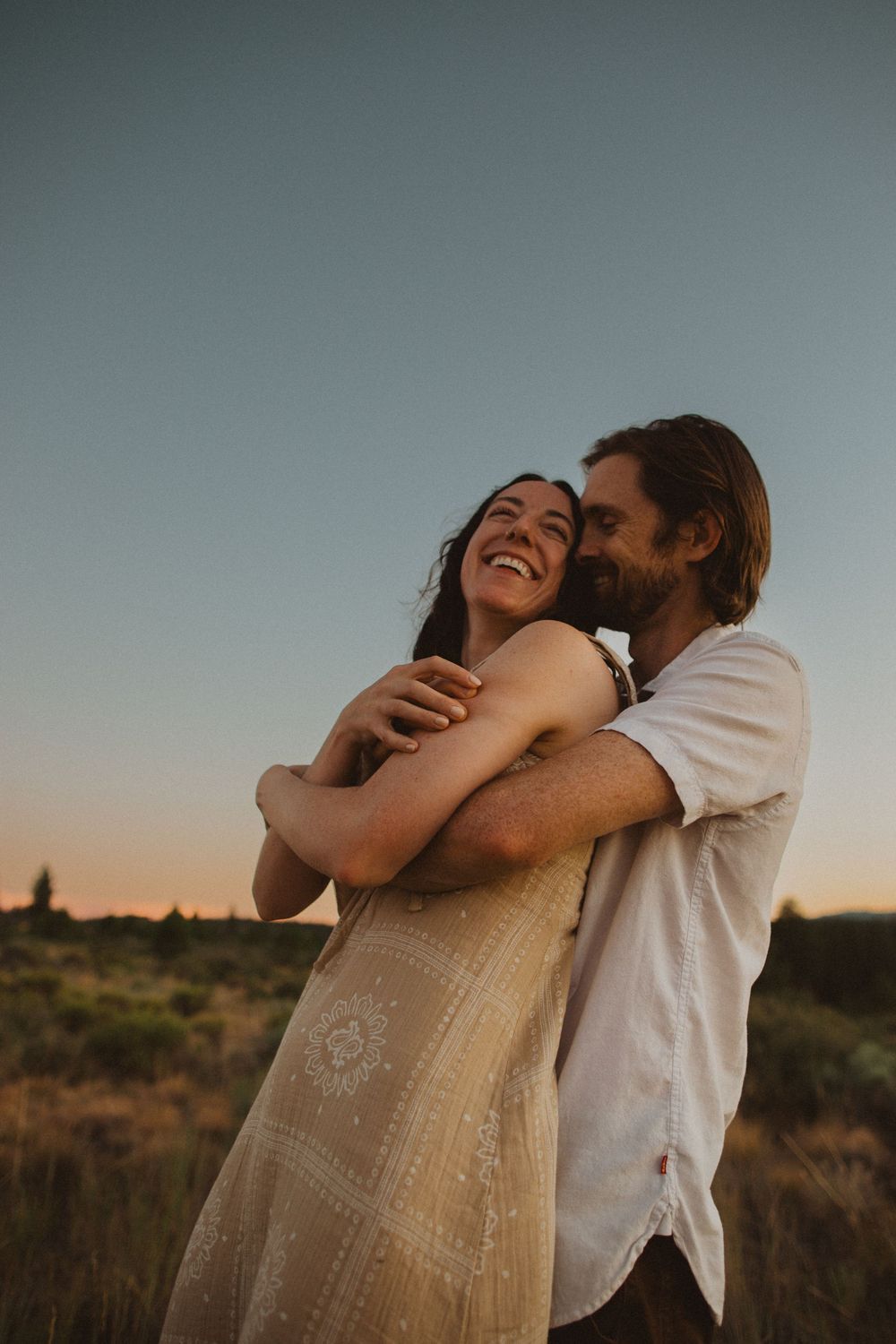 A couple shares romantic moments at sunset in a desert setting with warm lighting.