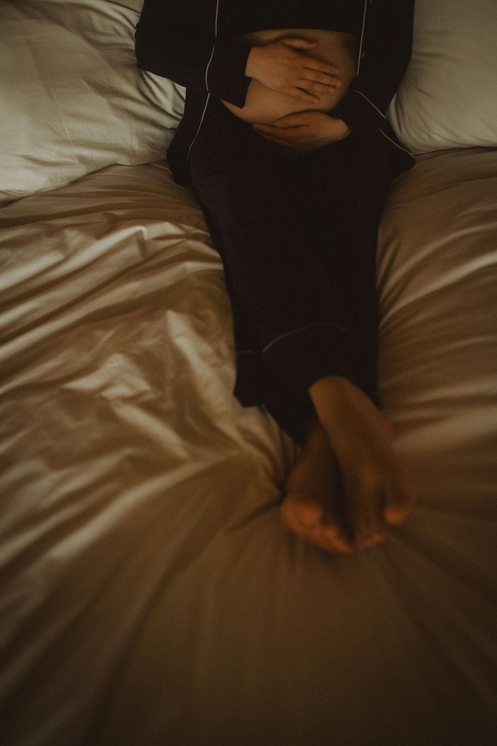Close-up of wrinkled white bedding sheets in dark lighting creating dramatic shadows and texture.