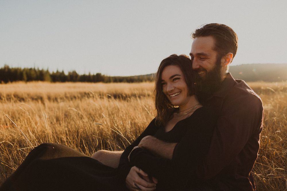 A couple sharing an intimate moment in a sun-drenched wheat field.