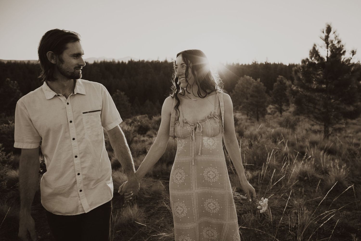 A romantic couple shares an intimate moment against a desert backdrop at sunset.