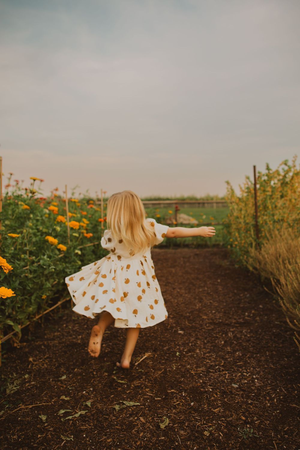 A playful sequence showing someone twirling in a floral dress among garden flowers.