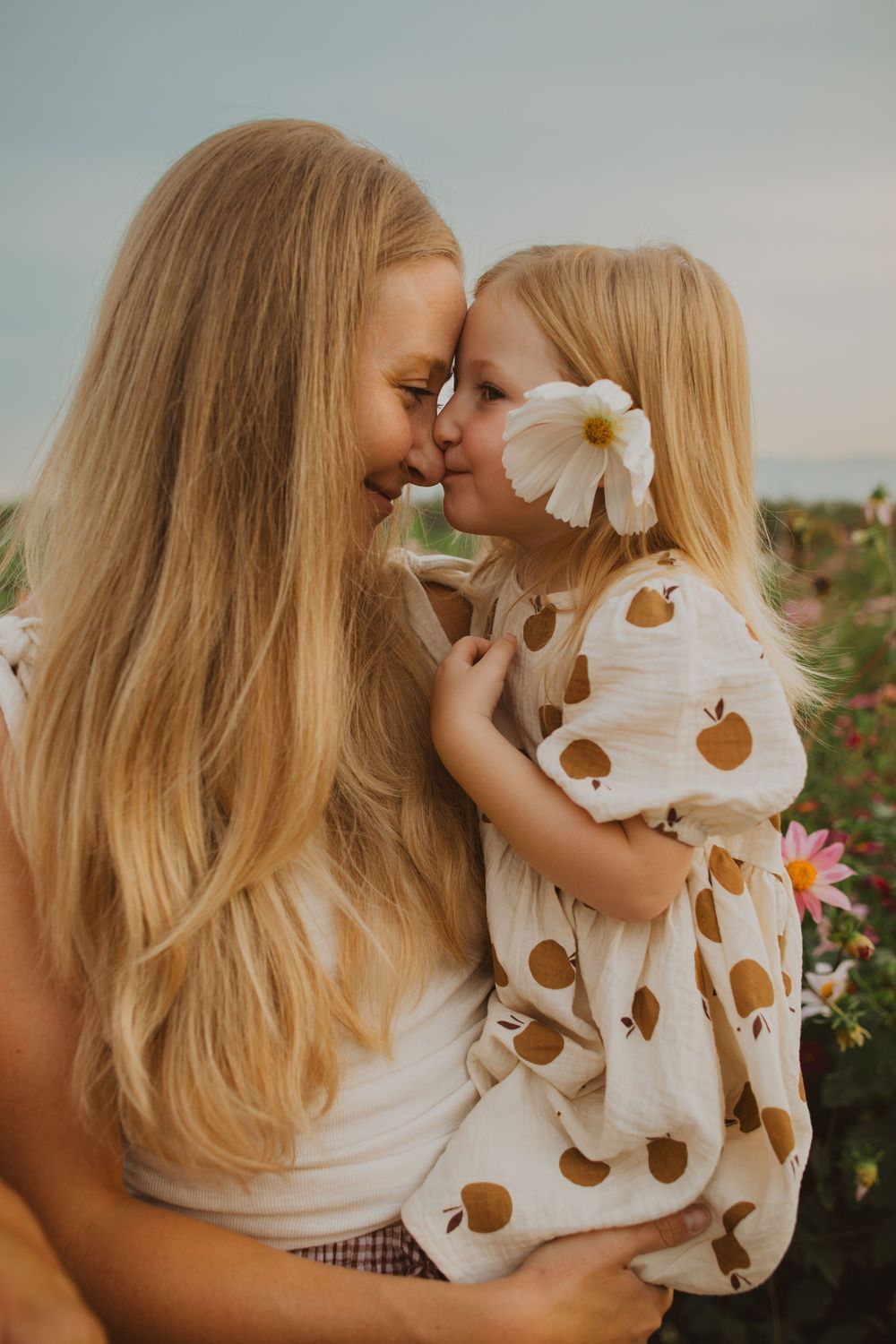 Sweet moments captured between parent and child among blooming flowers at sunset.