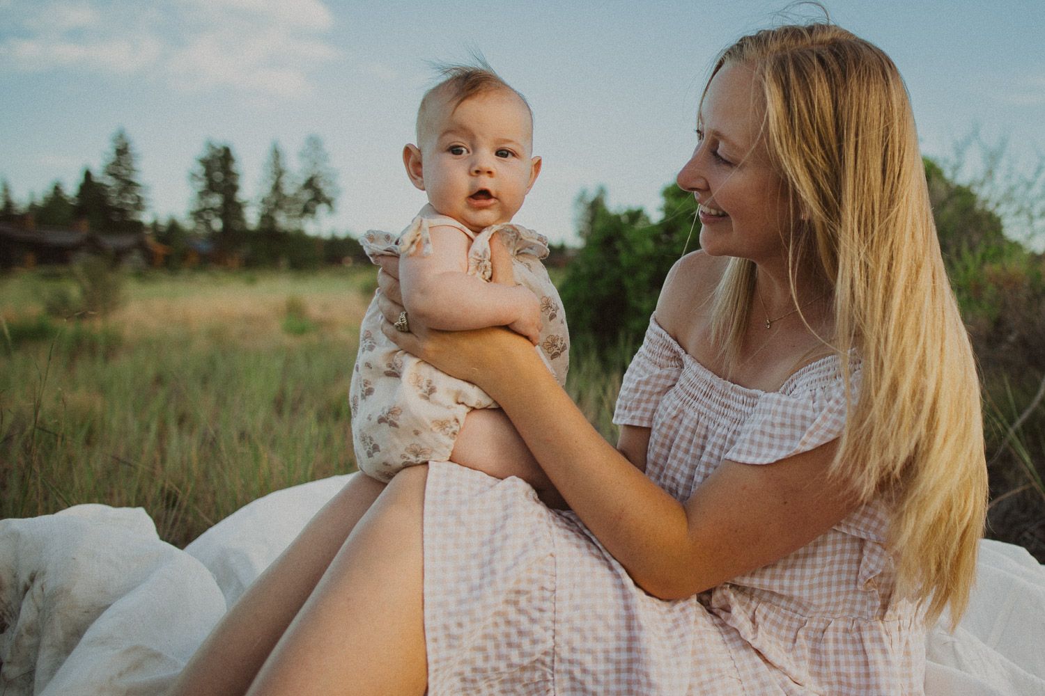 Summer photoshoot in a natural field setting with white gingham dress details.