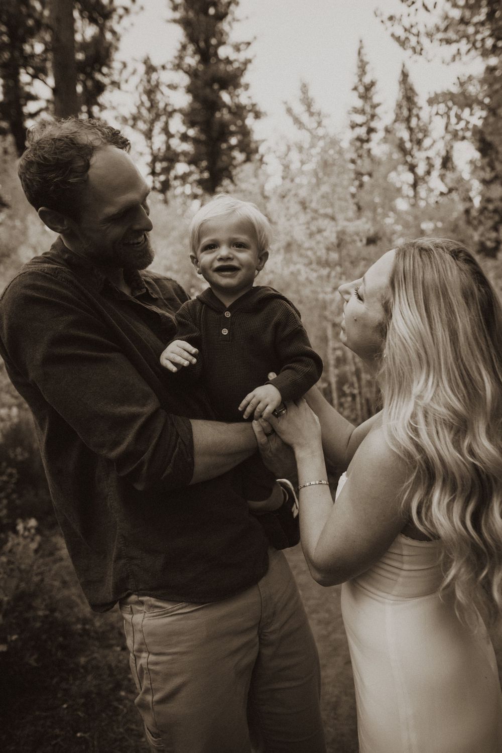 A tender family moment captured in black and white against a forest backdrop.