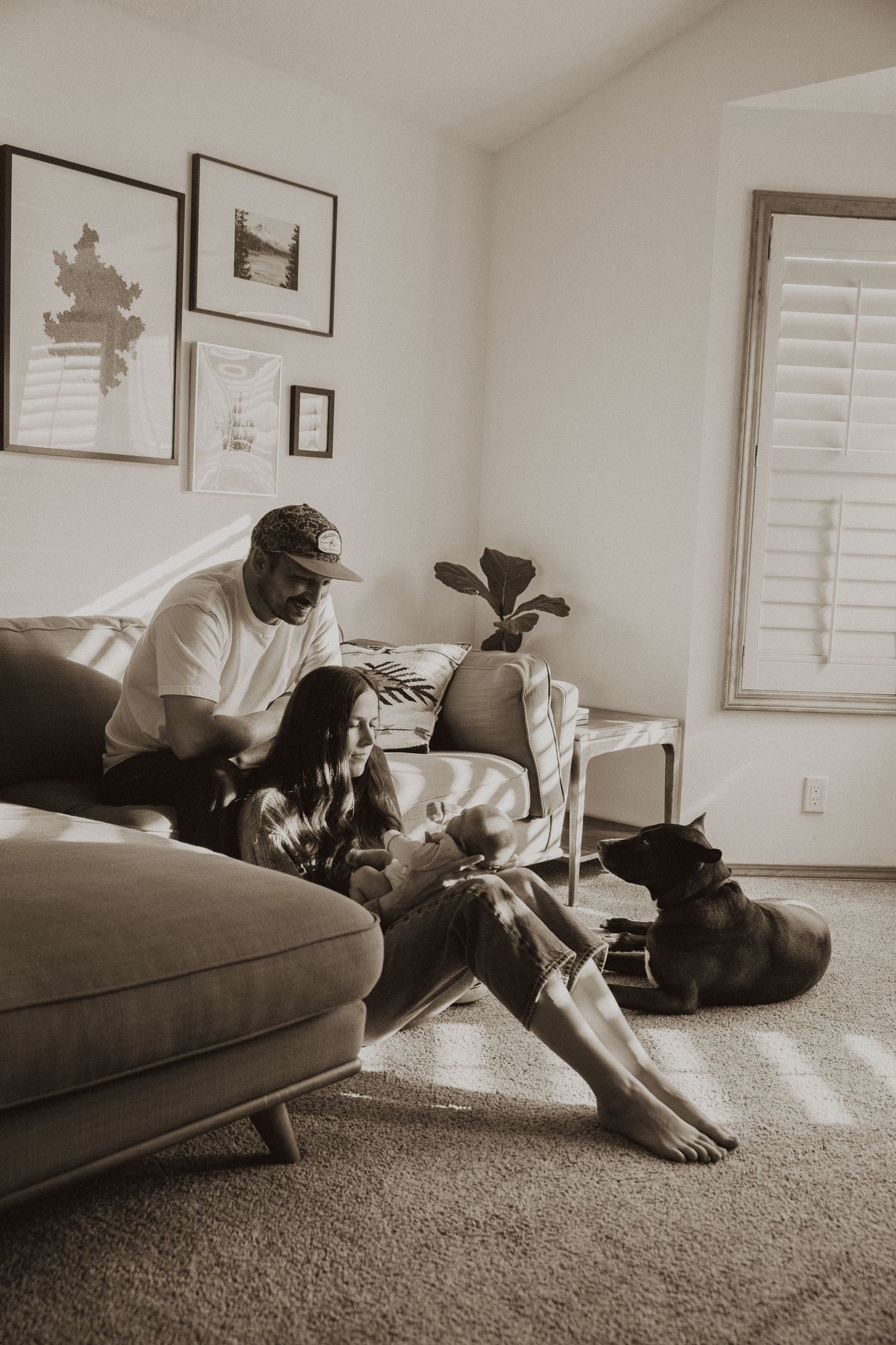Couple relaxing on couch with dog in cozy living room, sepia-toned home lifestyle photo.
