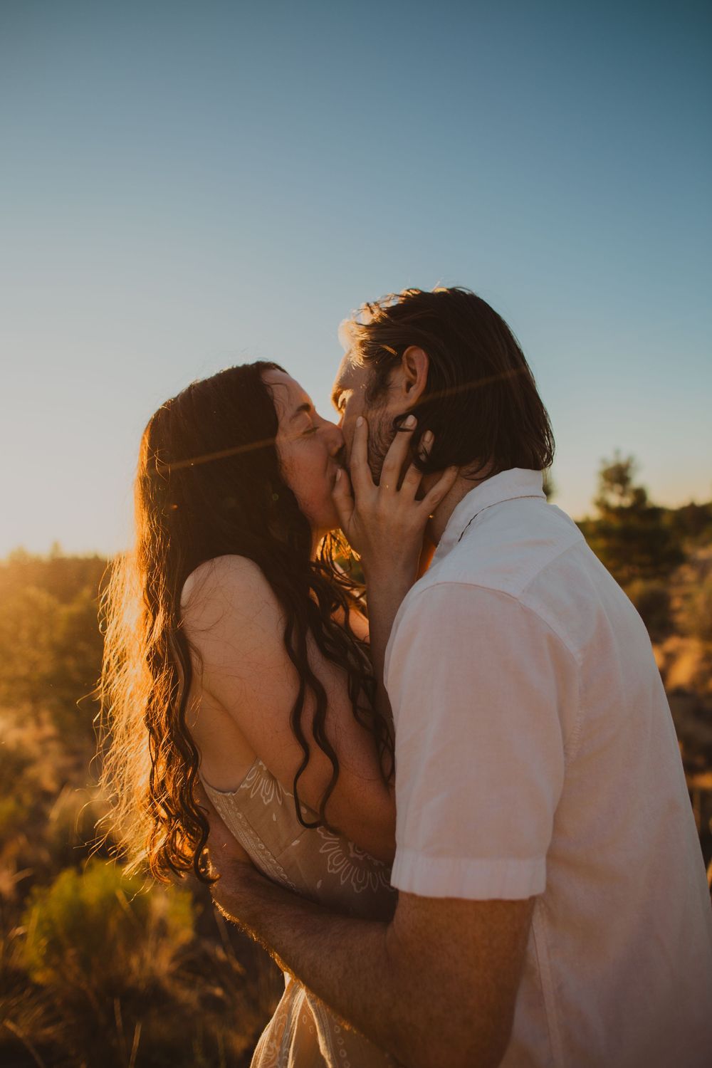 A couple shares intimate moments during sunset in a desert landscape.