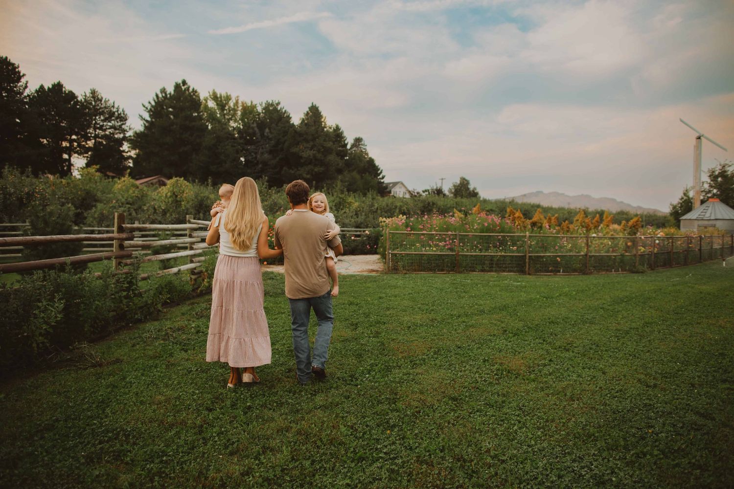 A scenic view of a garden path with people walking among flowers and trees.