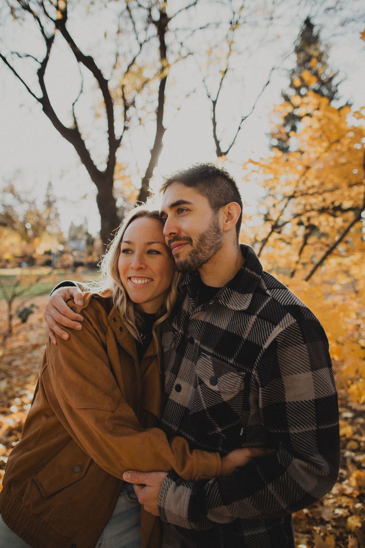 Cozy autumn portrait session featuring a couple in plaid and brown jackets among fall foliage.