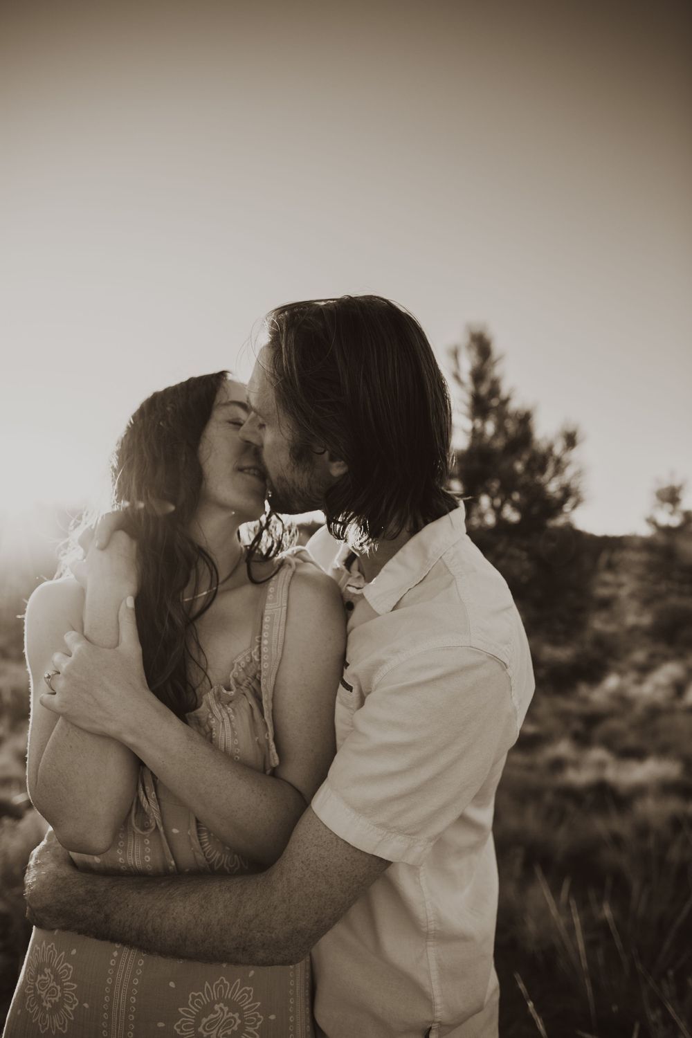 A couple shares intimate moments in black and white photography against a natural backdrop.