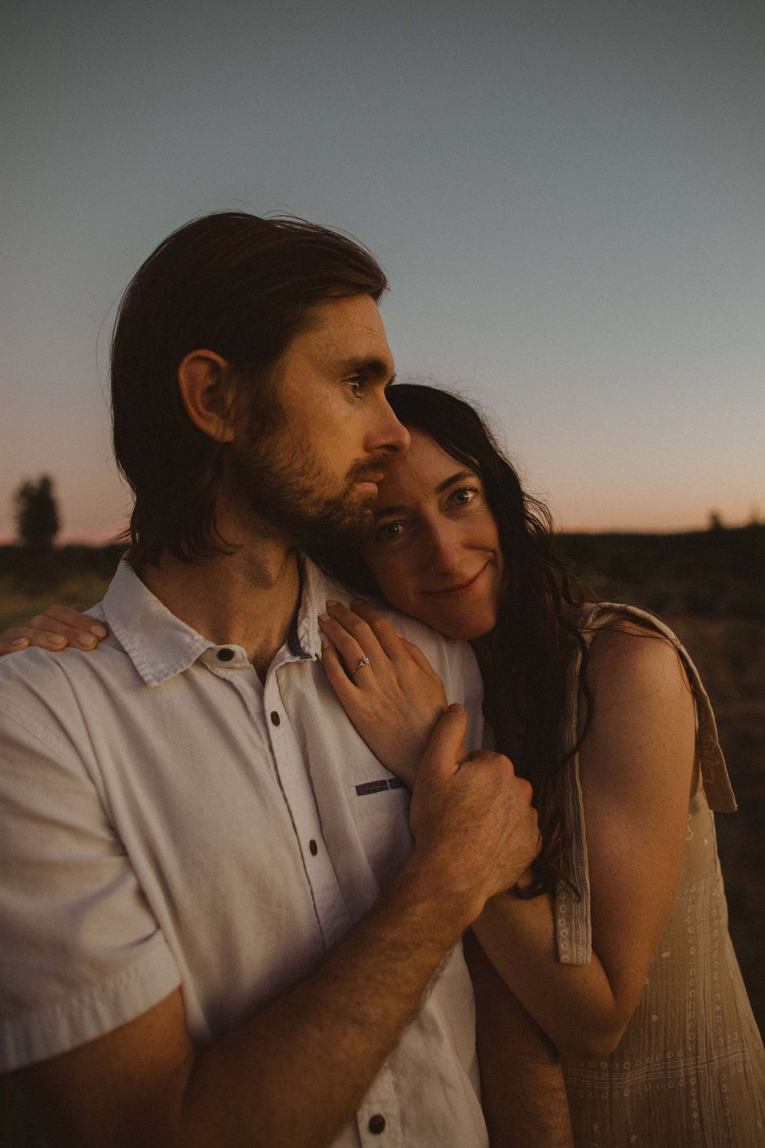 Two people share tender moments in warm evening light amidst desert brush.