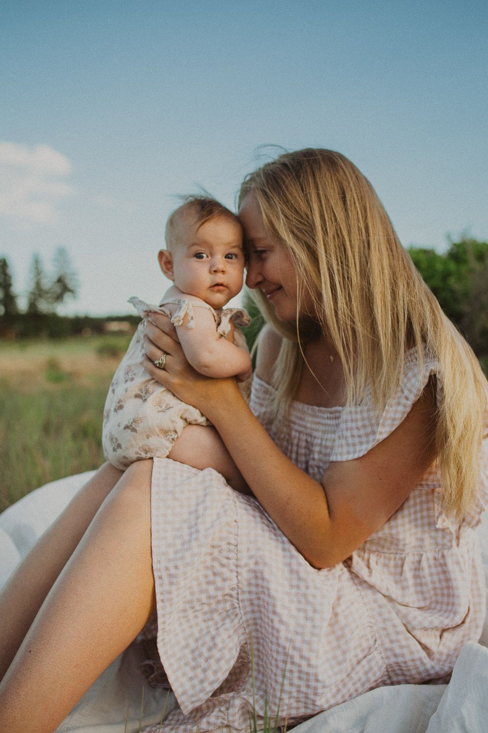 Intimate outdoor family moments captured against a bright blue summer sky.