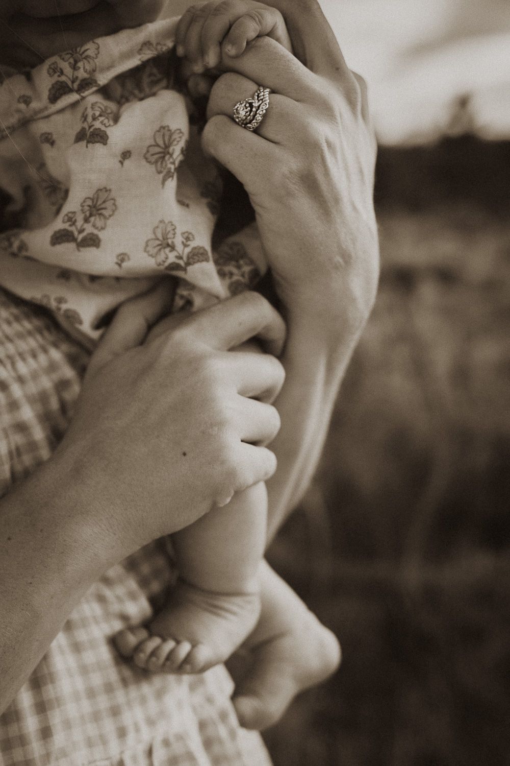 Close-up sepia toned image showing gentle hands and tender moments.