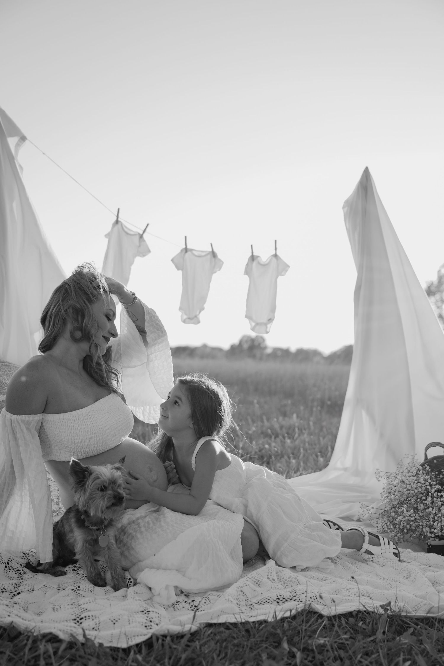 Black and white photograph of laundry drying on a clothesline in a field on a sunny day.