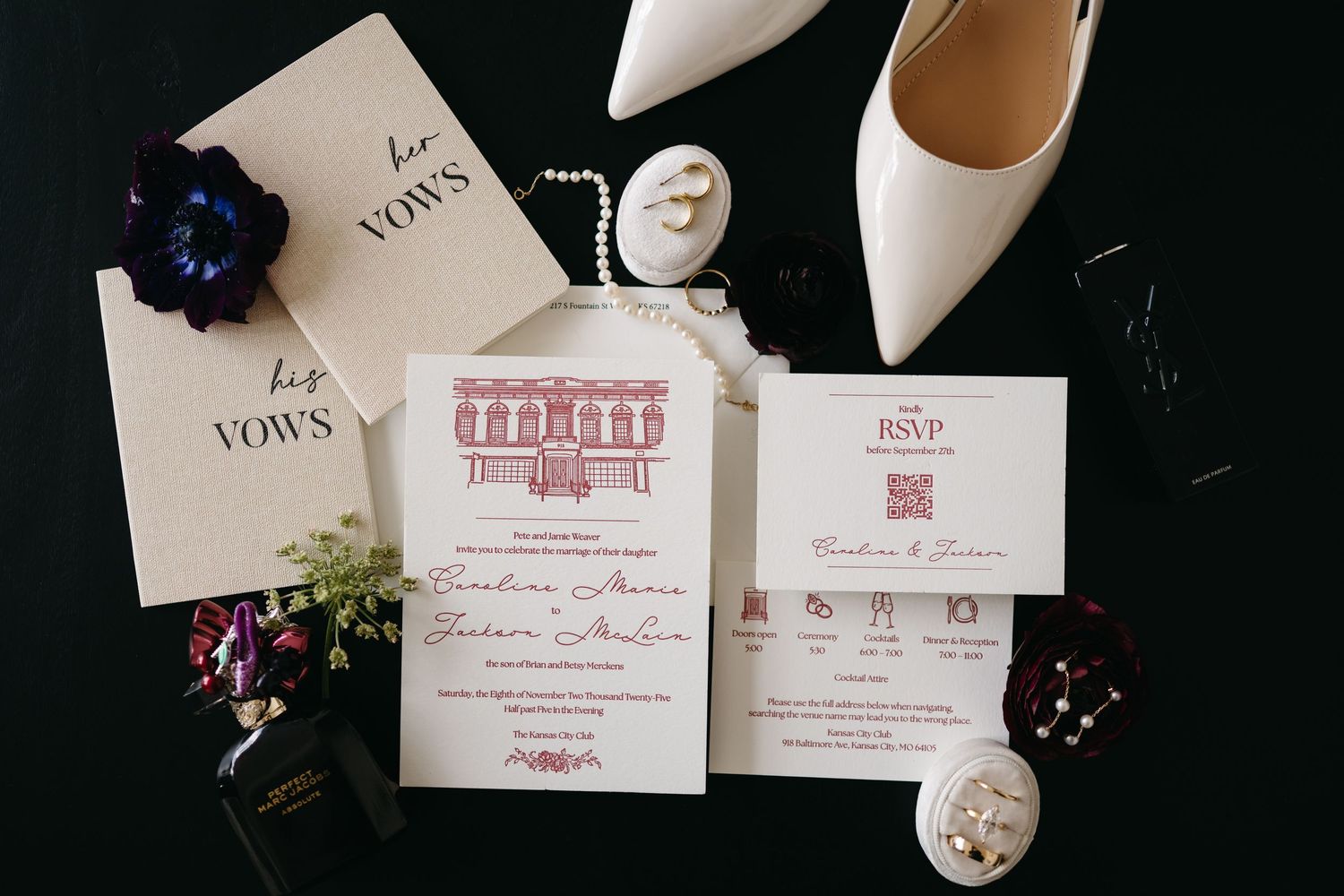 Elegant wedding invitation suite with RSVP card, vow books, white heels, pearl bracelet, and floral accents on black background.