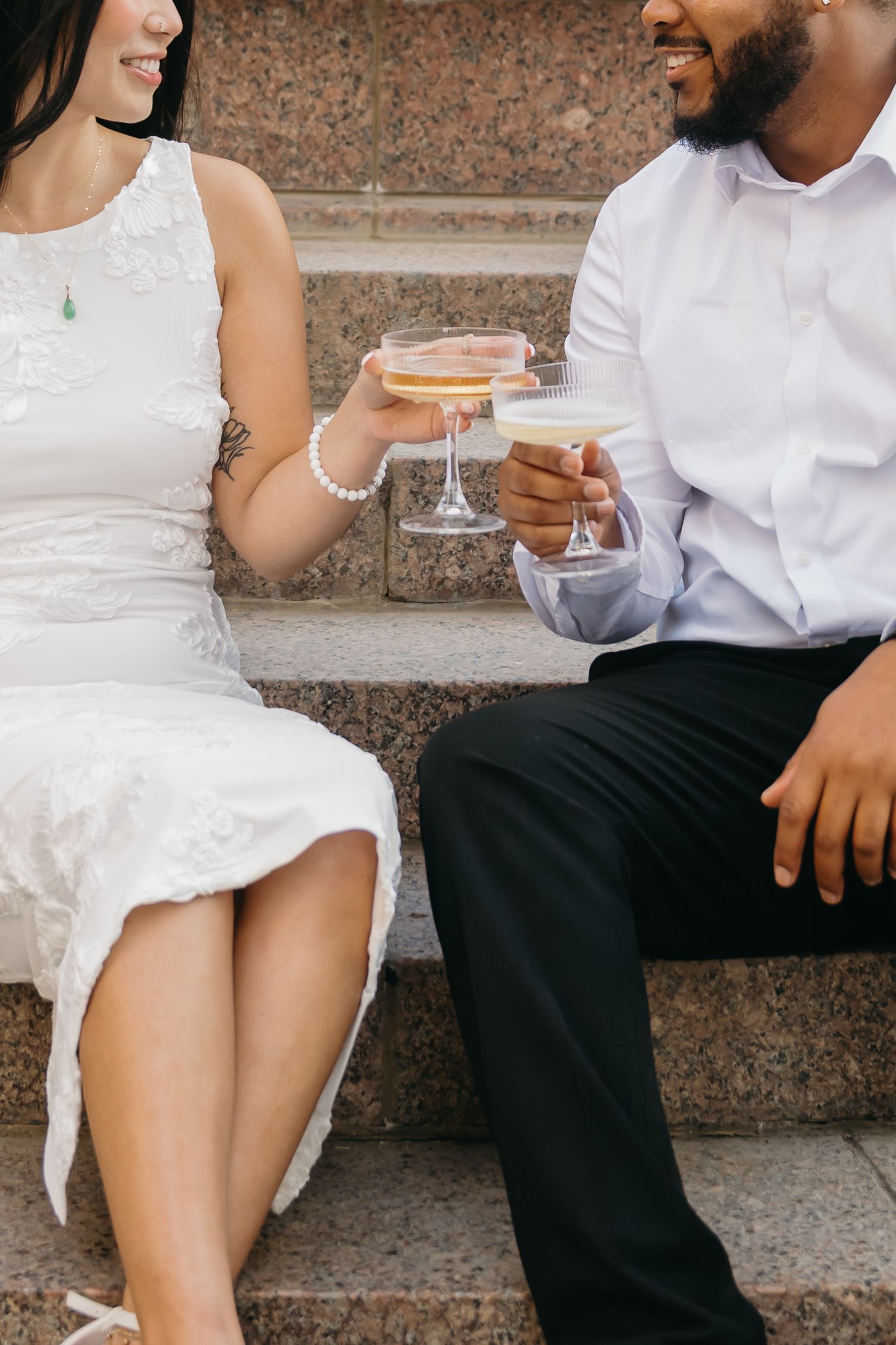 Couple sitting on stone steps sharing drinks and snacks at casual outdoor gathering.