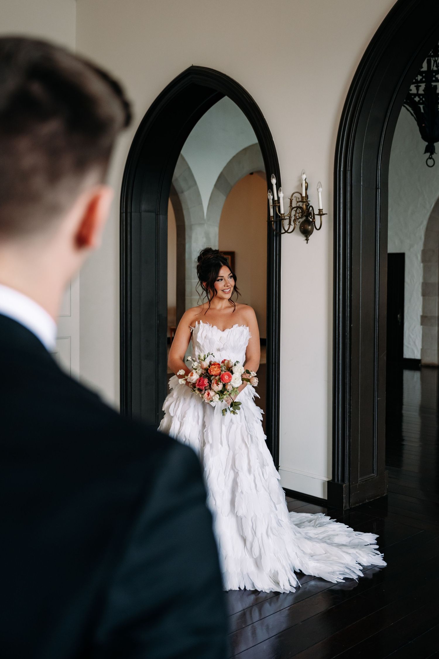 A romantic first look moment between newlyweds in an elegant arched hallway with a flowing white wedding gown.