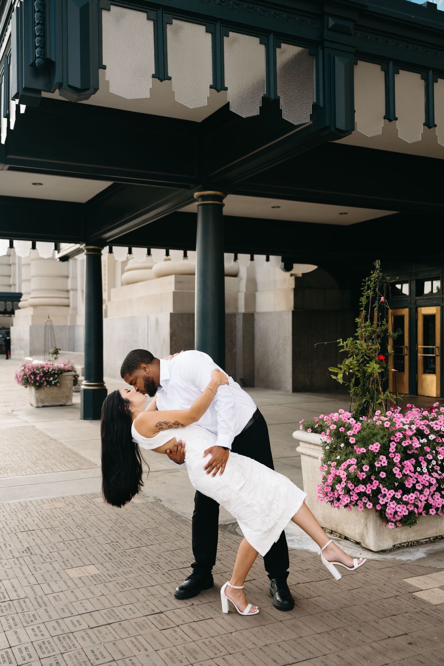 Romantic dip pose with pink flowers in the background.