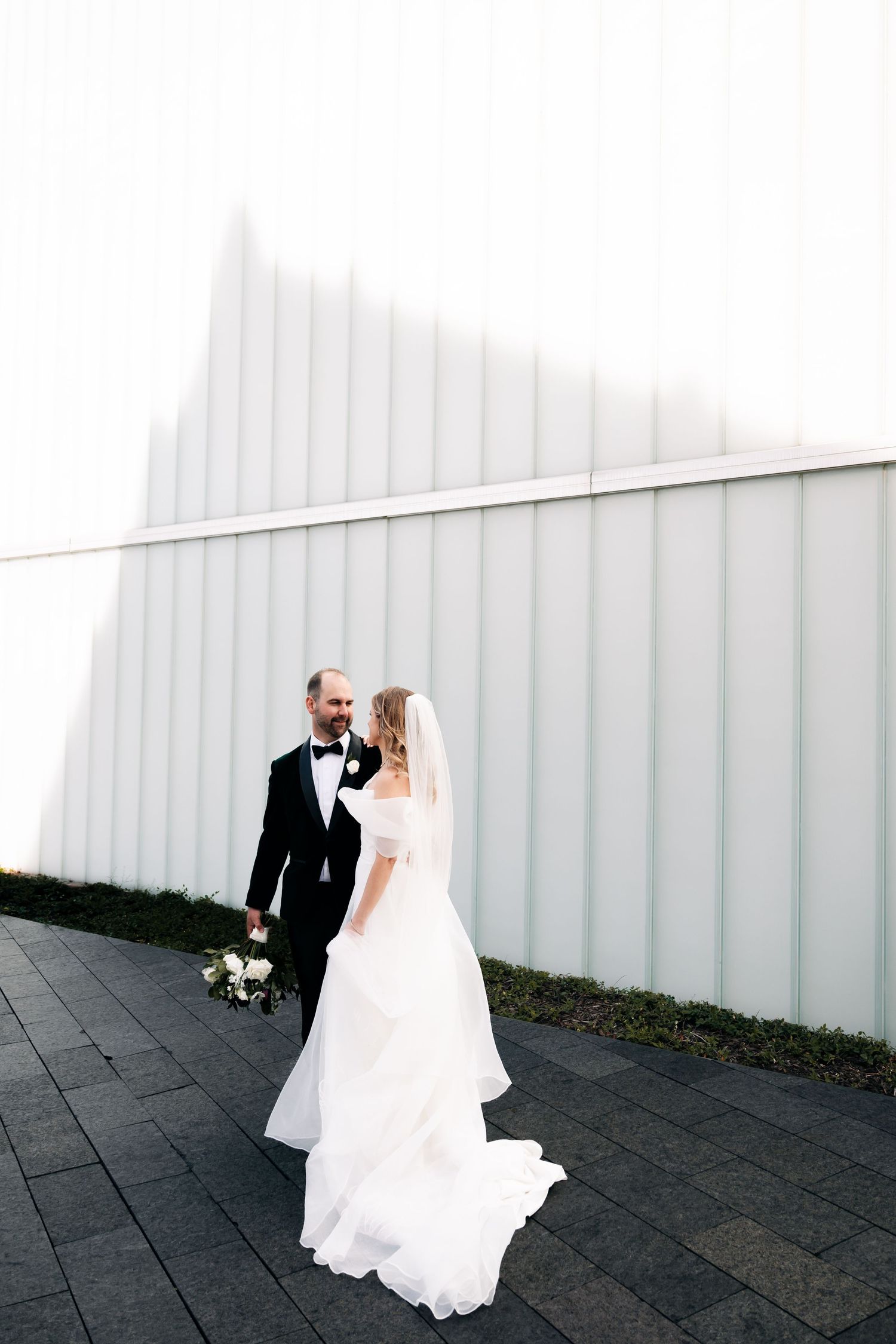 Modern wedding photography against minimalist white architectural backdrop.