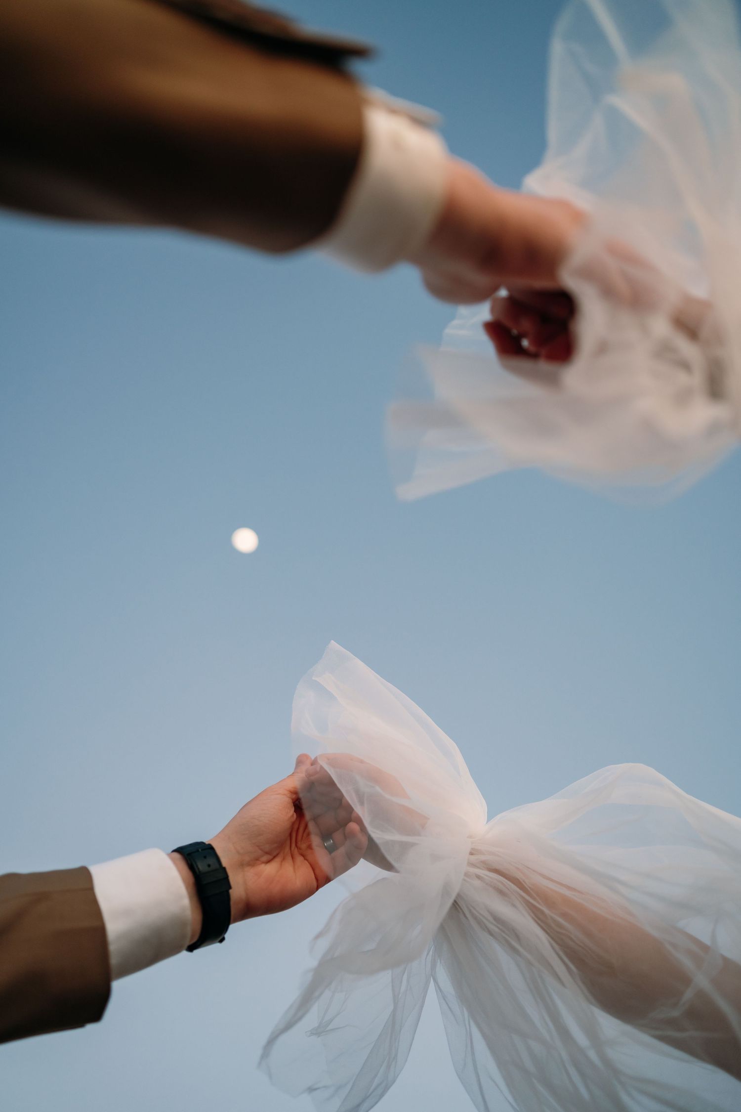 Flowing white tulle fabric against bright blue sky.