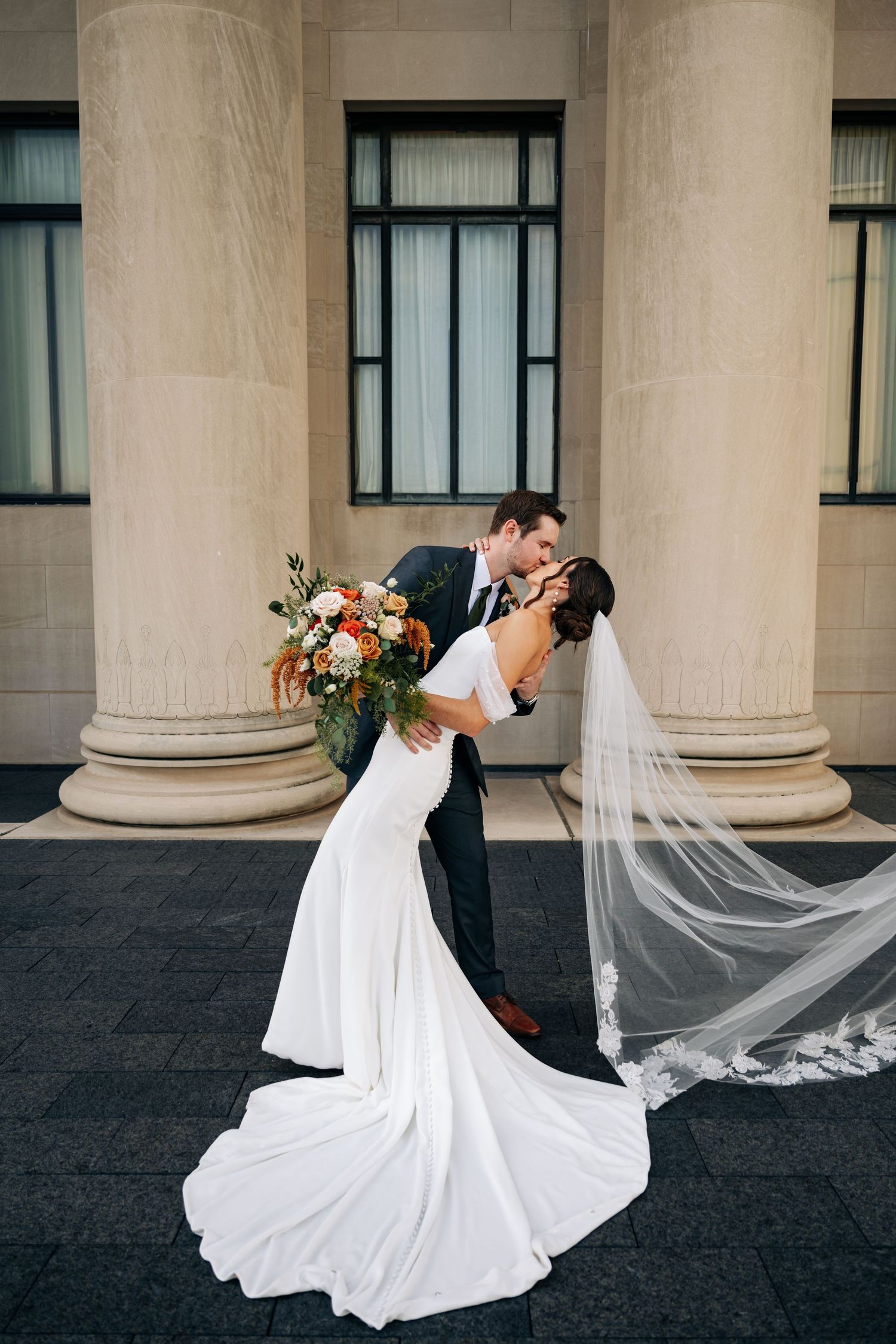 Romantic wedding couple shares intimate dance poses against classic architectural columns.