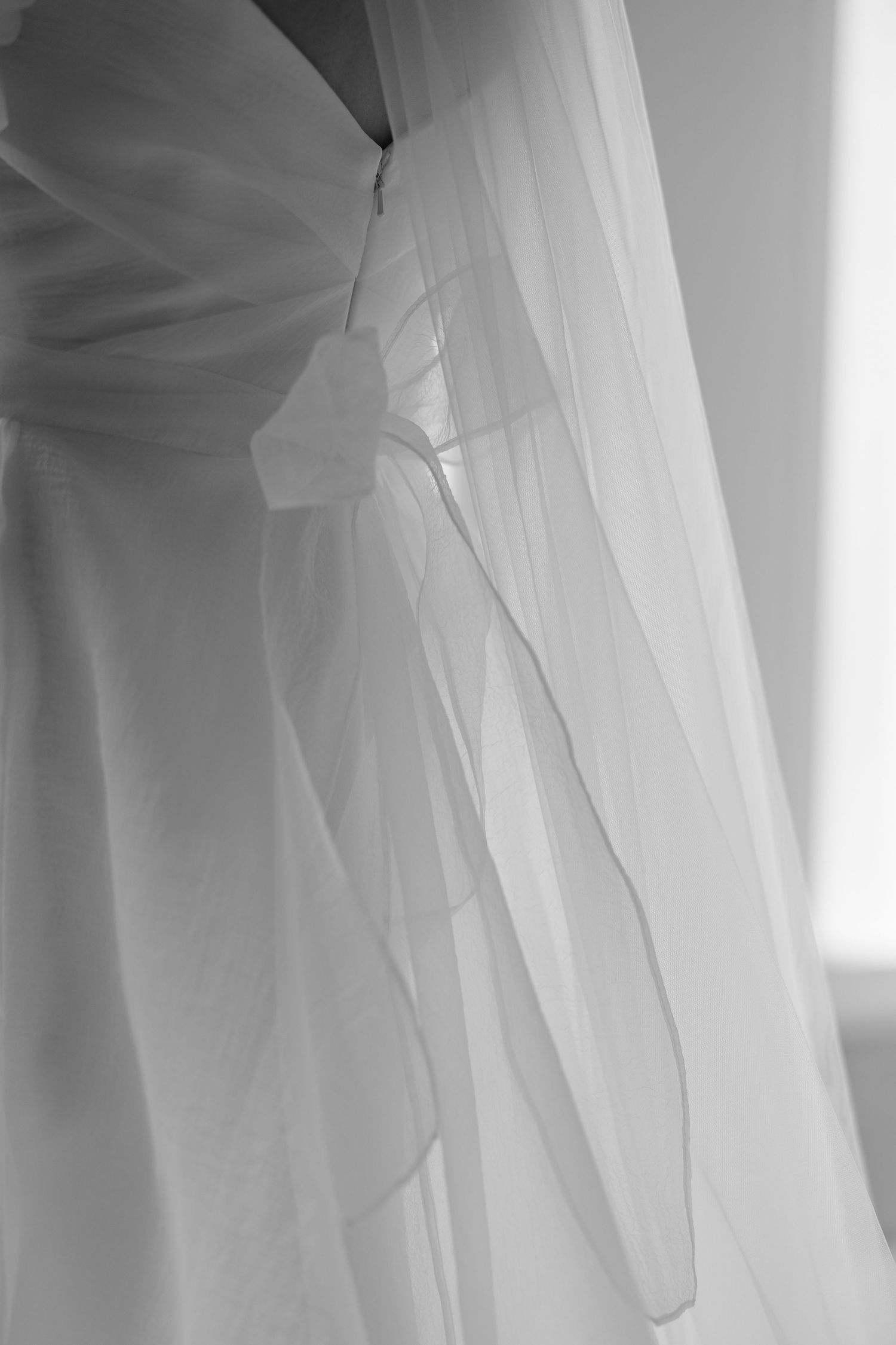 Ethereal close-up details of a flowing white wedding dress veil in natural light.