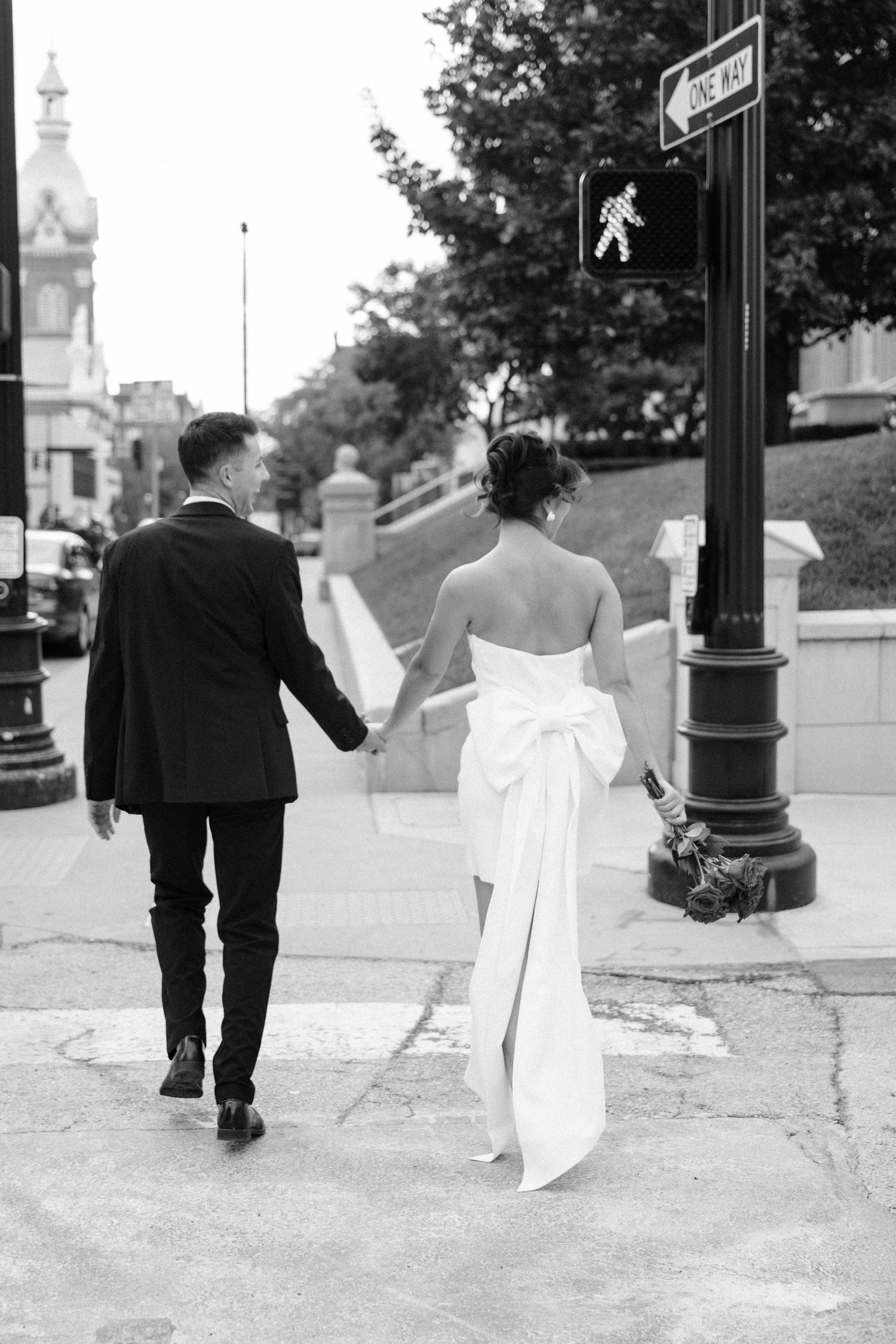 Black and white photo of a couple walking away on a city sidewalk.