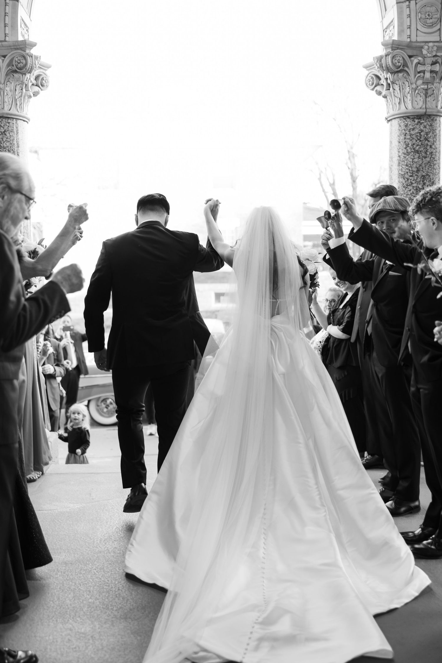 Black and white wedding photo showing couple walking out of Church among guests.