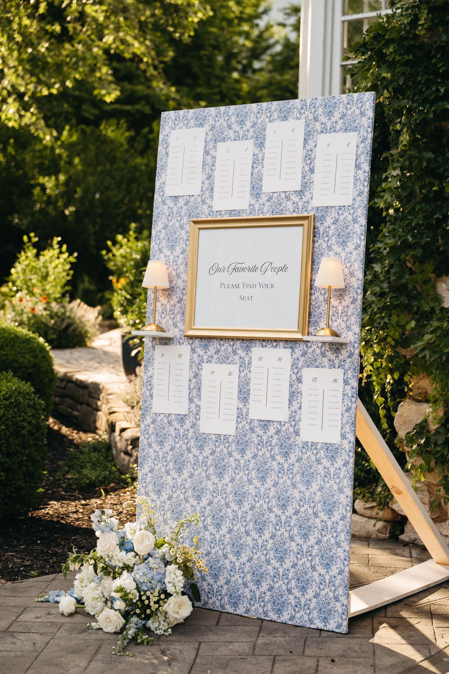 Wedding seating chart display with blue damask pattern and floral decorations shown from multiple angles on stone patio.