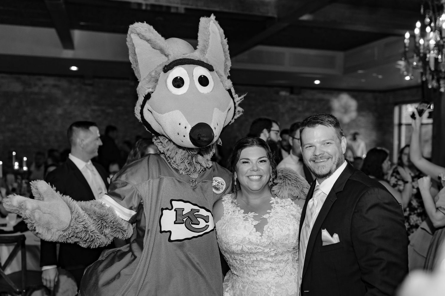 Wedding reception celebration featuring KC Chiefs mascot with guests.