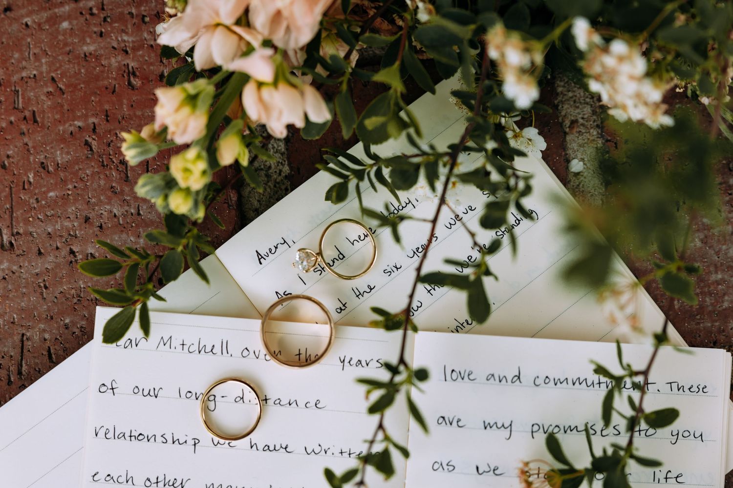 Wedding rings artistically photographed with handwritten vows and delicate floral details.