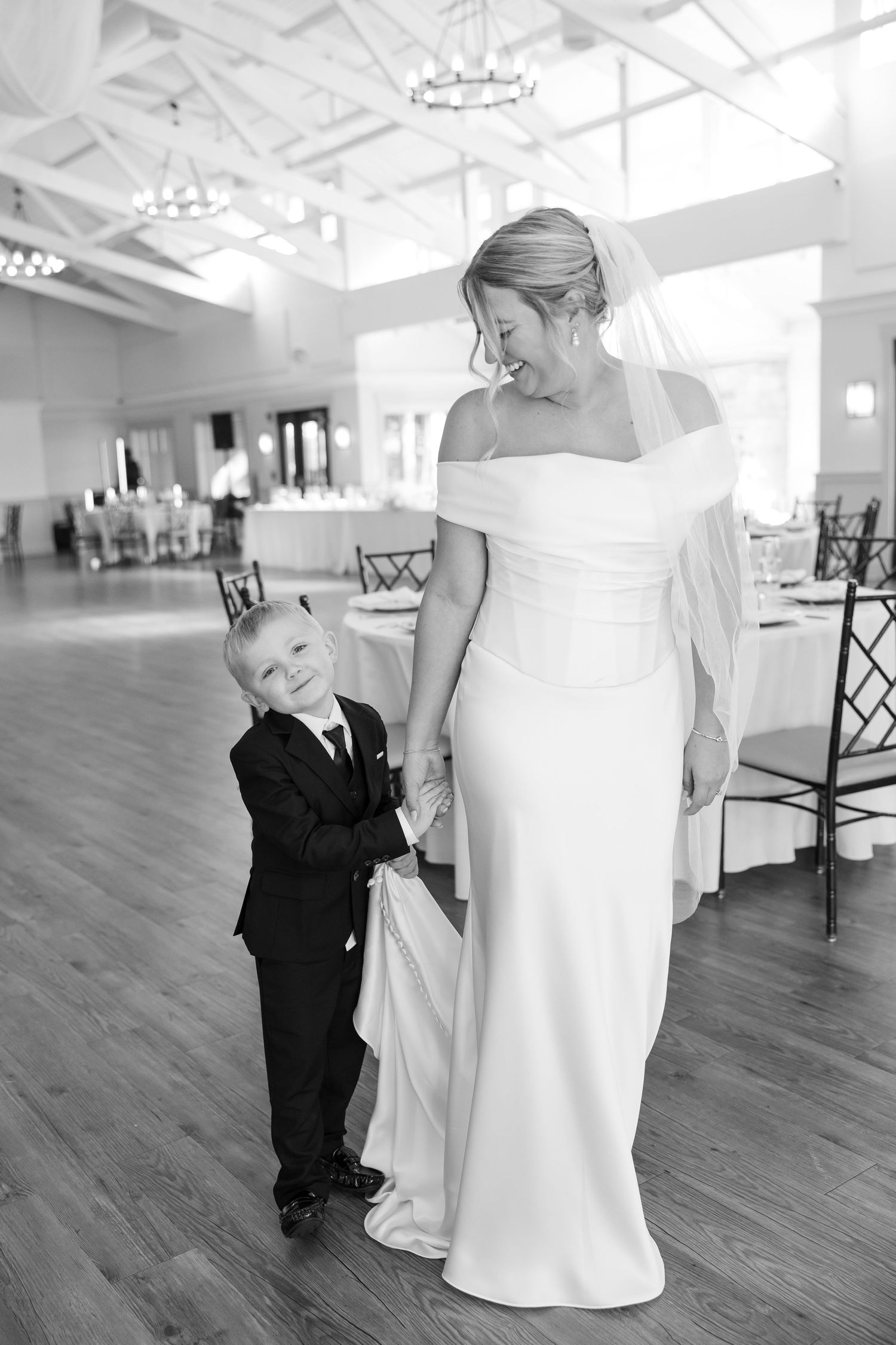 Sweet moment between a bride in an elegant white gown and young son in formal attire.