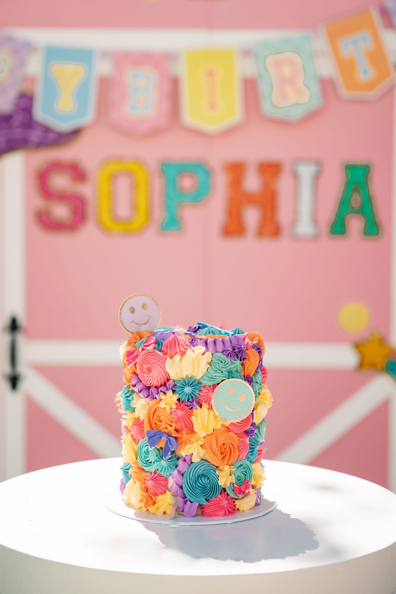 Colorful birthday cake with vibrant rose swirls in pink, blue, and orange frosting.