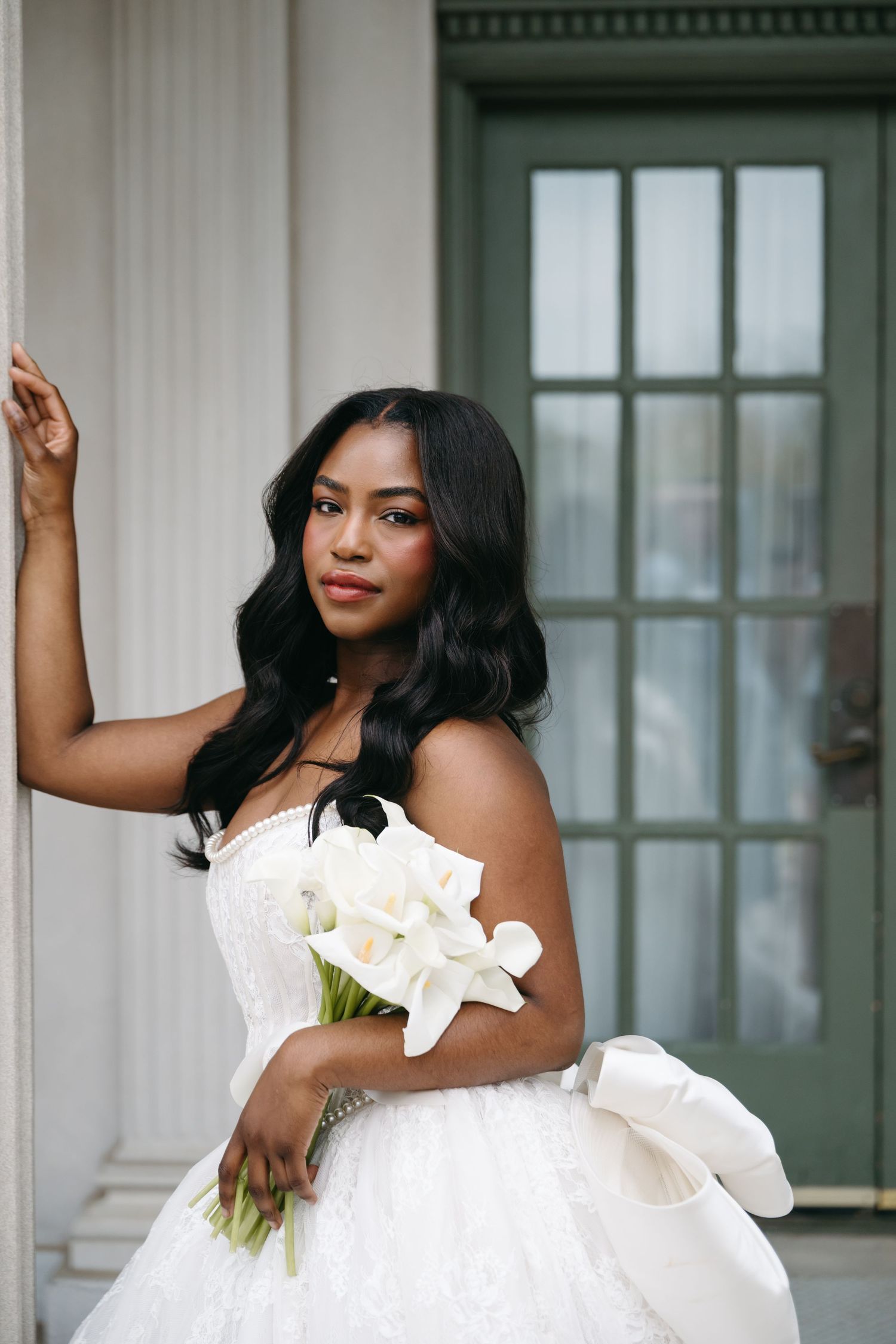 Bridal portraits in white ruffled dress against classic architectural backdrop.