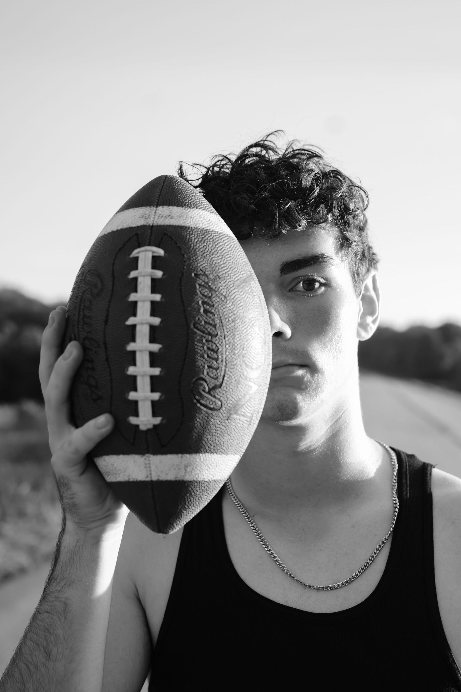 Black and white artistic portrait series featuring a football held against the senior high school football player's face