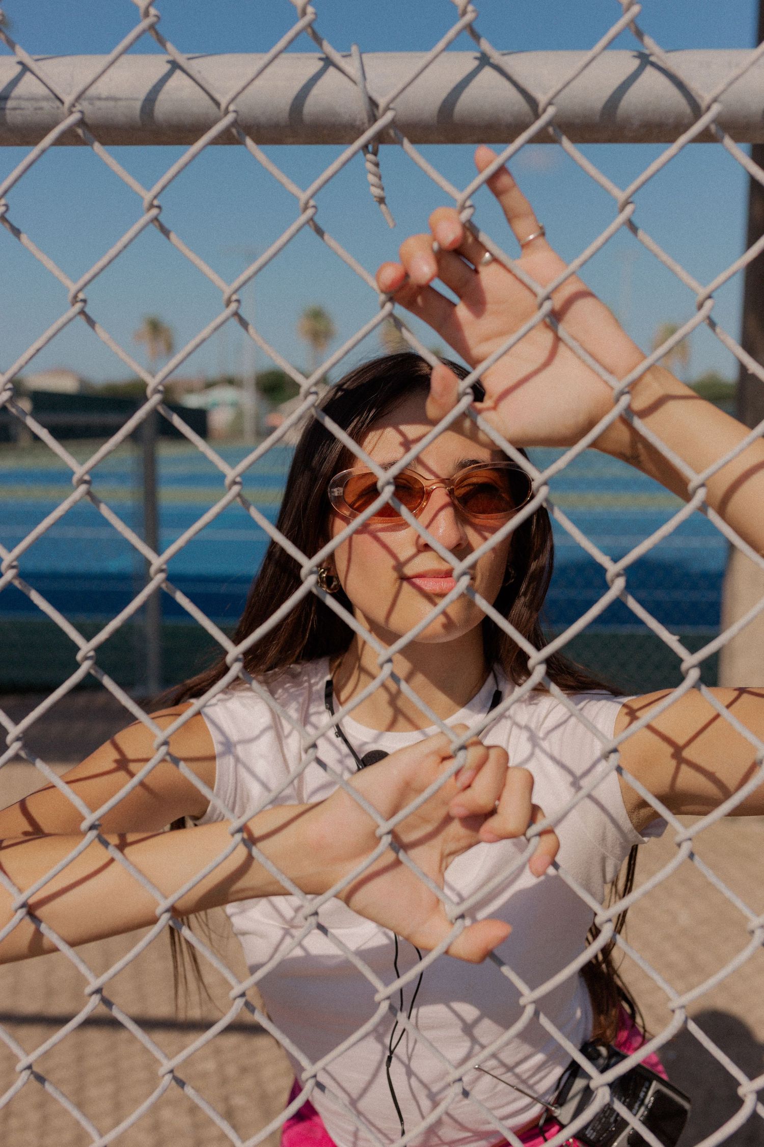 hispanic girl with brown hair posing at a tennis court in Galveston Texas for musician branding photo shoot