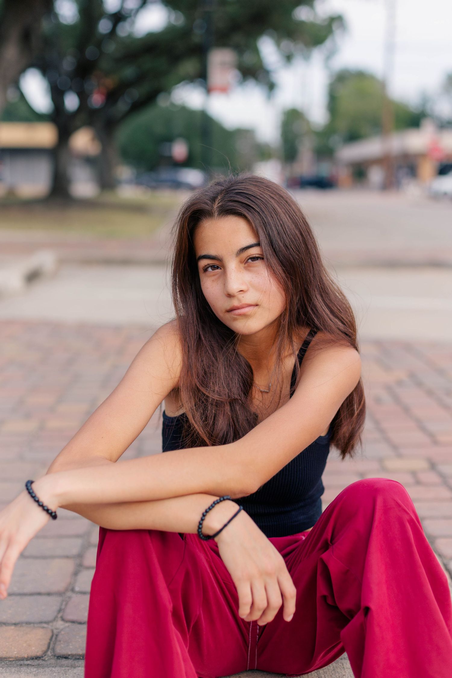 hispanic girl sits on a curb in old town Katy Texas for high school senior photos