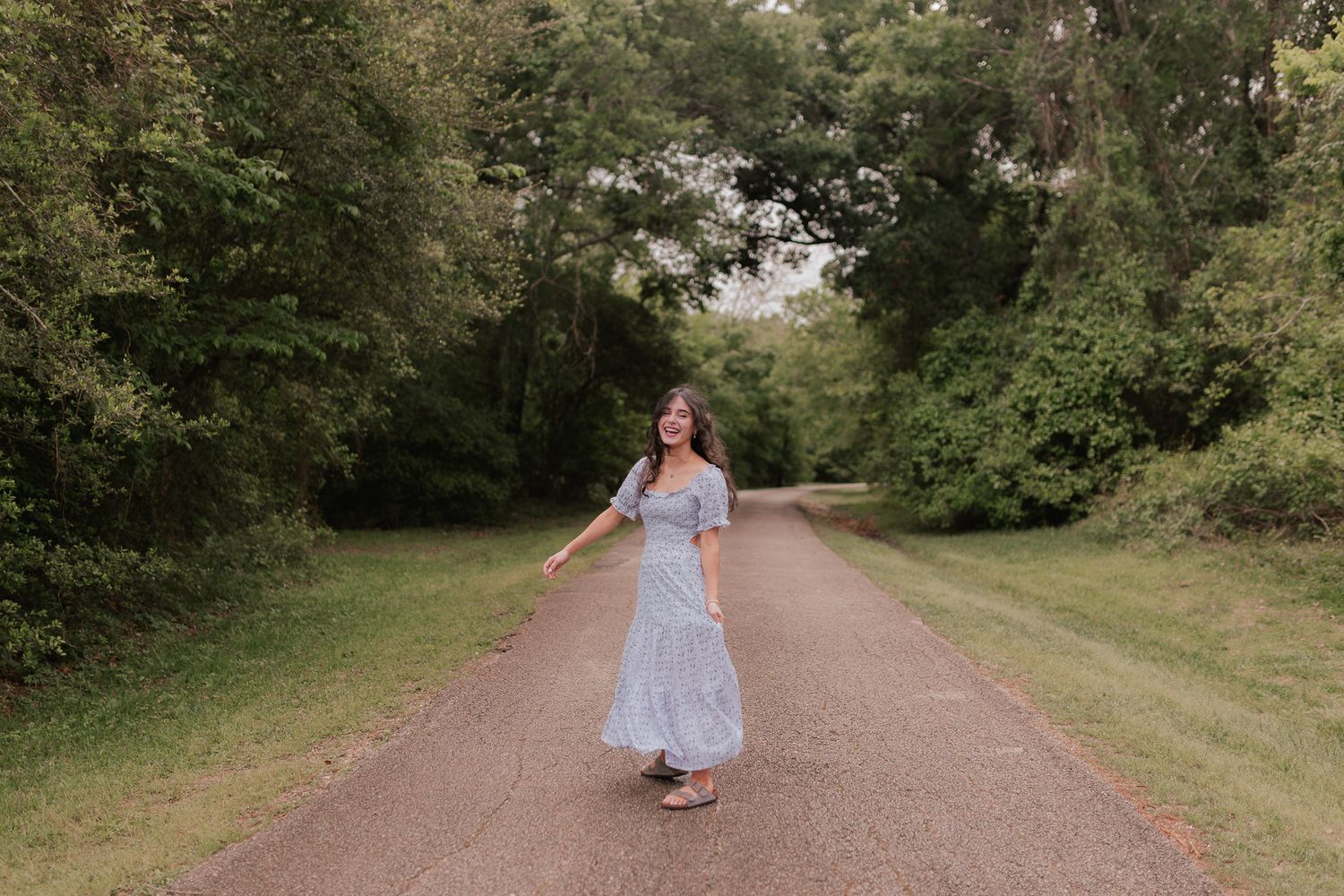 highs cool senior girl spins around in long purple floral dress for senior photos in friendswood Texas
