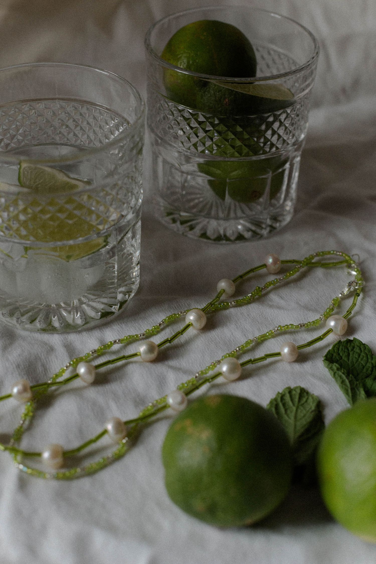 handmade necklace placed with limes and cocktail glasses for jewelry business branding photoshoot