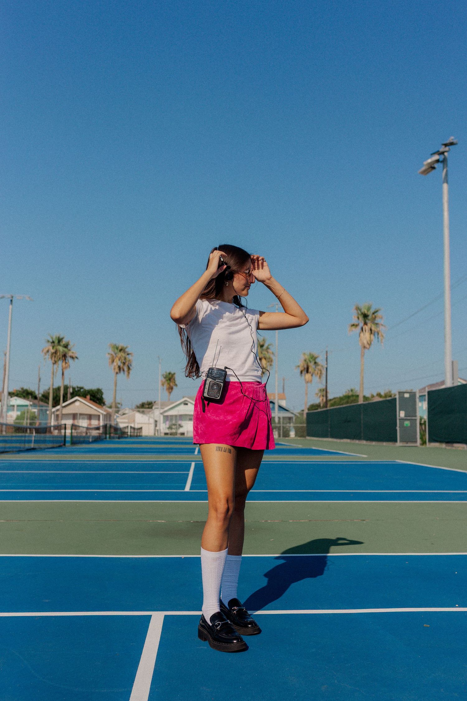 hispanic girl with brown hair posing at a tennis court in Galveston Texas for musician branding photo shoot