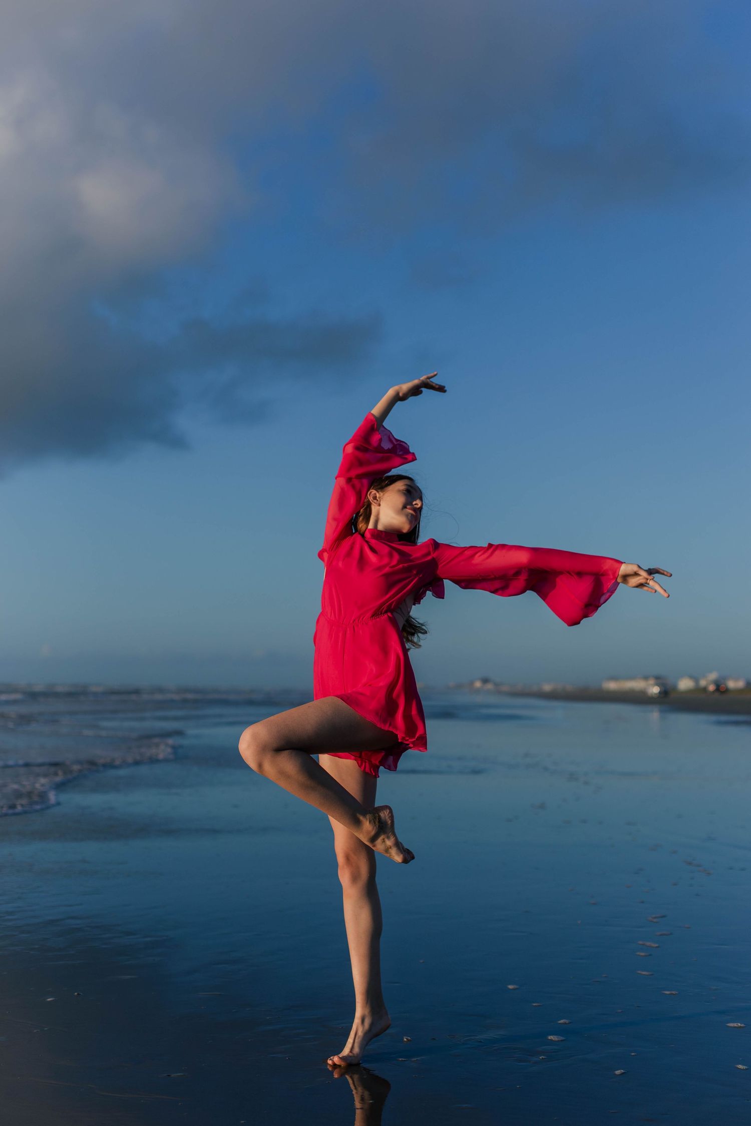 dancing girl poses in hot pink romper at the beach in Galveston Texas at sunrise for sweet sixteen photos