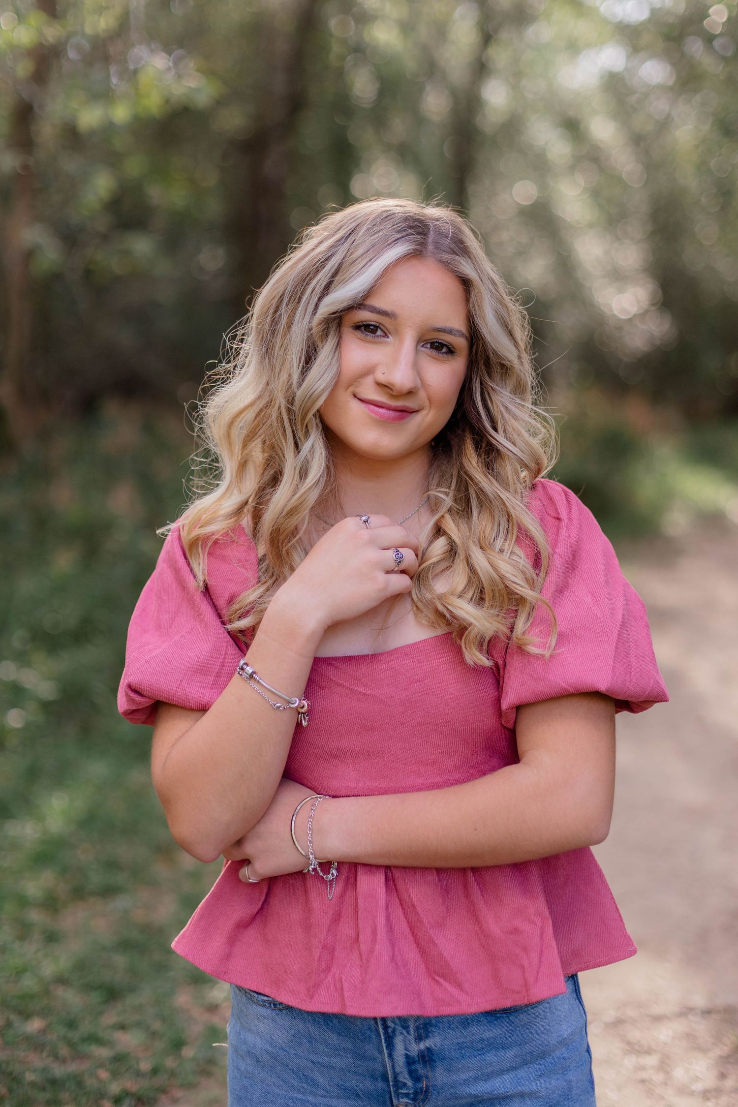 blonde haired high school girl in dusty rose pink top smiles and poses for senior photos in friendswood Texas