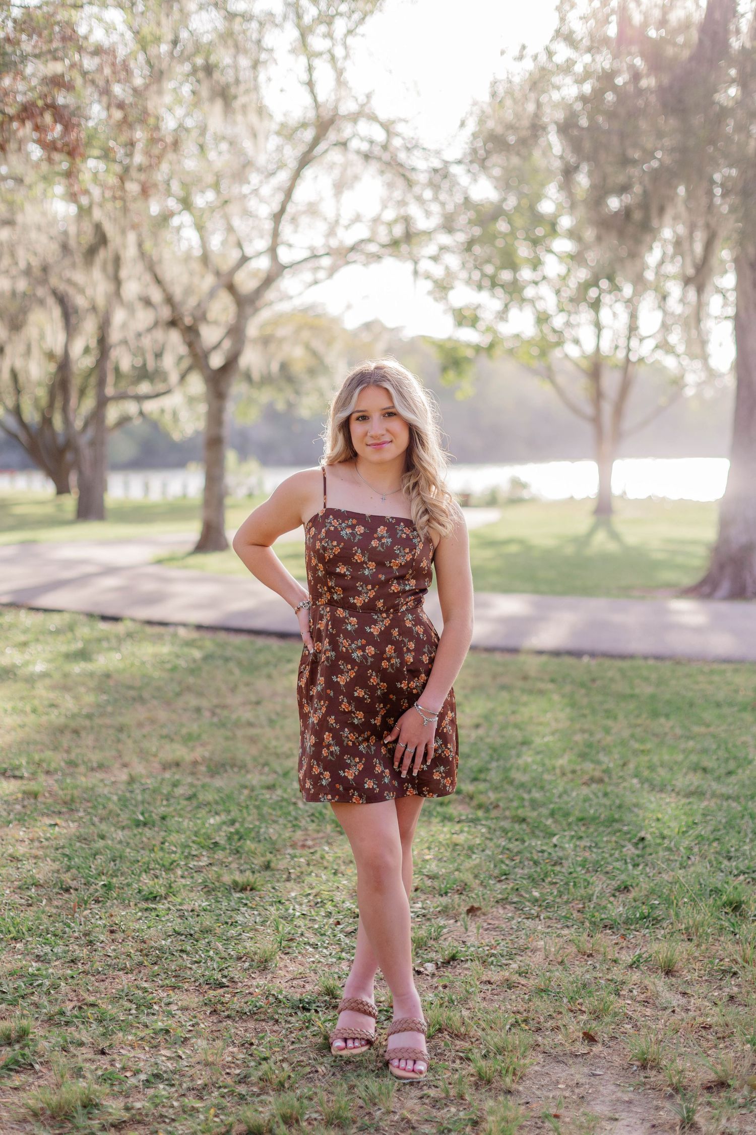 high school senior girl at a park in friendswood Texas with the sun setting behind her as she smiles